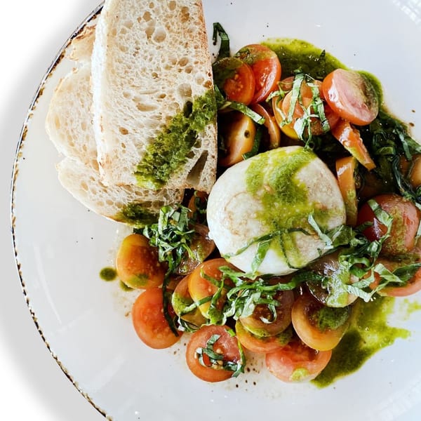 Olia Restaurant's Mediterranean burrata salad with sliced tomatoes, pesto, and toasted bread.