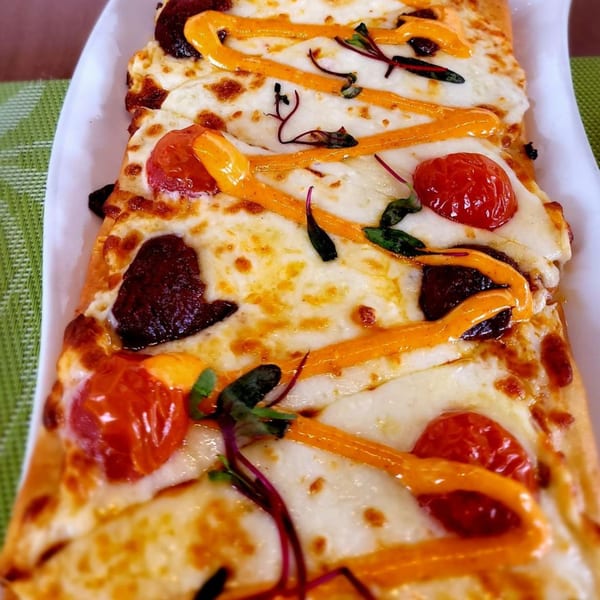 Olia Restaurant's Mediterranean flatbread with melted cheese, cherry tomatoes, dark olives, and orange sauce.